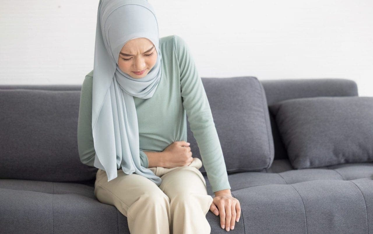 woman in pain, sitting and holding her belly