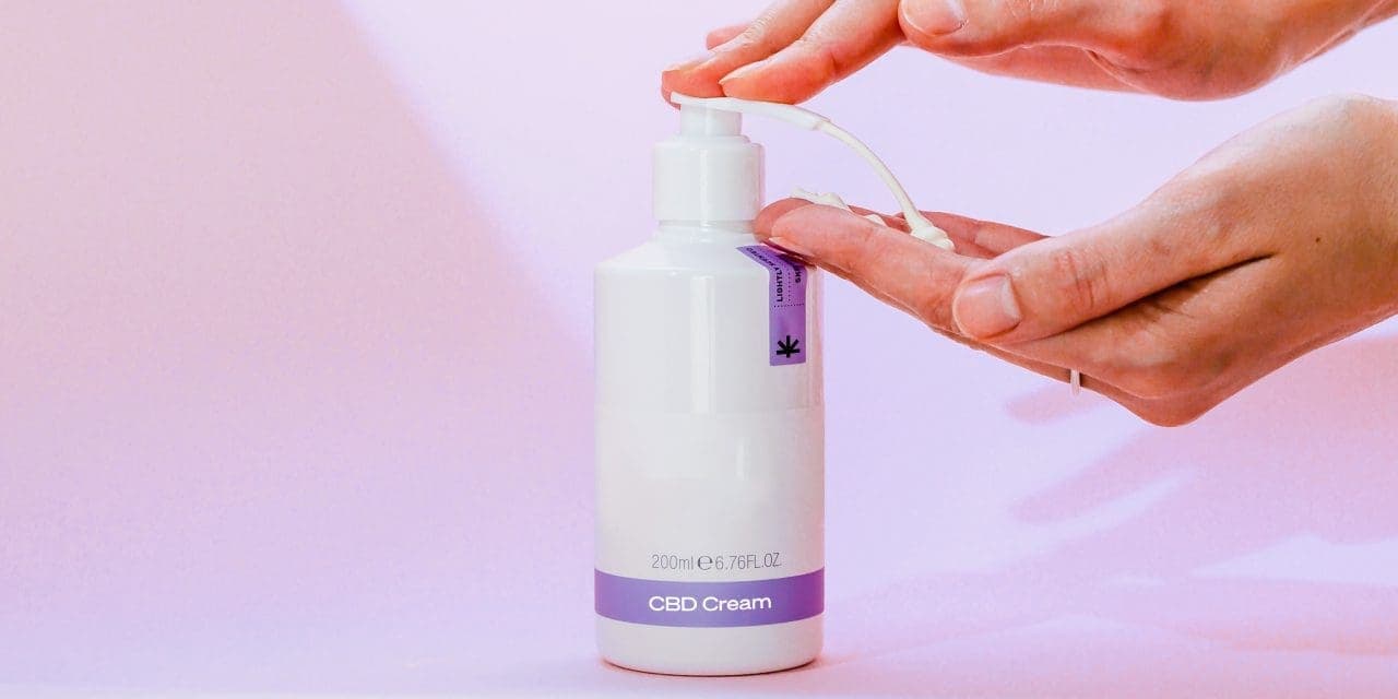 a hand pumping CBD cream from bottle